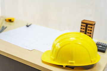 An architect's desk with blueprints and a white hardhat sits empty, ready for the next project. No...