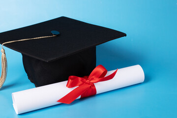 Graduation cap and diploma on blue background, high school graduation, academic success celebration