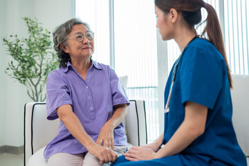 Fototapeta premium Asian young nurse taking care and talking mature female patient sitting on sofa in hospital. Healthcare concept.