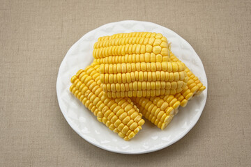 Raw corn kernels and cobs sliced on white plate
