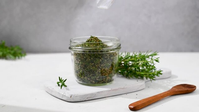 Mix of dried green herbs spice in a glass jar