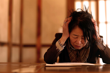 暗い部屋で老年の女性が破綻して頭を抱えている　Generative AI