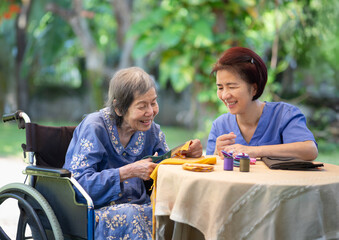 Elderly woman with caregiver in the needle crafts occupational therapy  for Alzheimer’s or dementia - Powered by Adobe