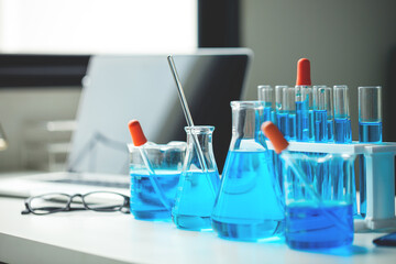 A table with a laptop, a few beakers and test tubes, and a blue liquid. The table is set up for a science experiment