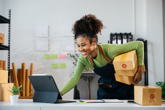 African Owner SME Small and Medium Enterprises woman seller happy and excited for selling new products and receiving the orders from customer via smartphone and laptop on shopping online application.