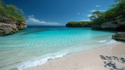 Fototapeta premium Serene tropical beach with clear turquoise water, white sand, and lush greenery under a bright blue sky, perfect for a tranquil getaway.