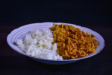 Plates of rice and instant noodles on a black background. Unhealthy combination of carbohydrates.