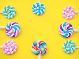 Colorful lollipops against a bright yellow background. Vibrant candy pops and space to add personalized text for party invitations