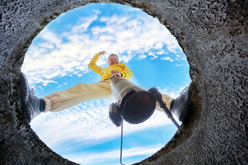 Homeowner plunges wastewater pump into sewage while standing on concrete ring of septic tank.