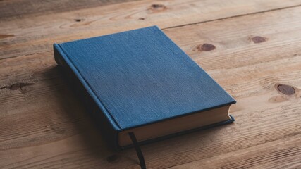 A simple blue book placed on a wooden desk, ready for reading or study.