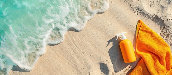 Bright summer beach holiday or travel lifestyle idea flat lay with sunblock spray and towel on the shore. Overhead view. Ample space for text
