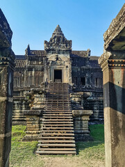 Majestic entrance of an ancient Angkor temple in Cambodia, featuring weathered stone architecture, intricate carvings, and wooden stairs leading to an ornate doorway