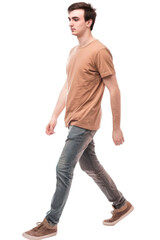 Young man walking with a neutral expression, wearing a brown t-shirt, gray jeans, and brown sneakers. Isolated on a transparent background. Suitable for casual fashion or lifestyle themes.