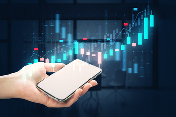 A hand holding a smartphone with stock market chart hologram, on a blurred office background, concept of technology and finance