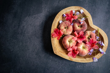 Peaches in a heart shaped wooden dish with fresh flowers