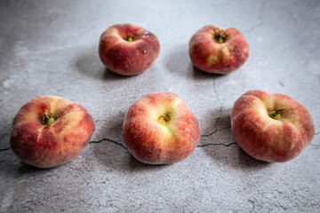 Five fresh peaches lined up on a kitchen worktop