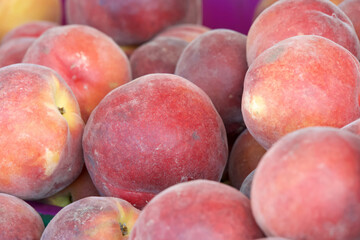 Close up on pile of fresh ripe sweet yellow peaches for sale at farmers market. View from above.