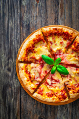 Pizza Serrano with cured ham, mozzarella cheese and mushrooms on wooden table
