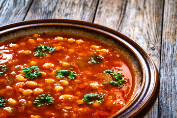 Moroccan cuisine - harira fresh vegetable soup with chickpeas and lentil on wooden table
