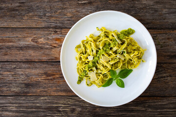 Pappardelle with basil pesto sauce sprinkled with grated Parmesan cheese served on white plate with...