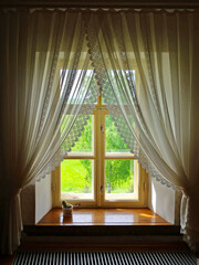 Wooden window with white curtains. Window with frilled curtains overviewing the garden. Retro home...