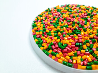 Colorful masterbatch granules mixed in a cup, isolated on white background.Color pigment carrier...