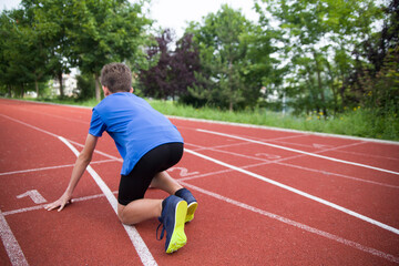 The athlete stands on the starting line on the track.