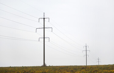 a high-voltage power line stretches into the distance through a sloping field. supply of energy from the power plant to the end consumer. energy security