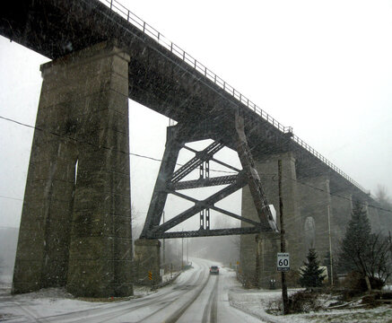 Driving under an old railway trestle bridge during a snowstorm.