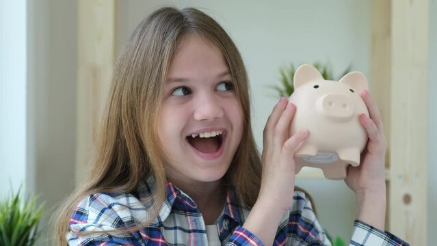 Cute little preteen girl holding and shaking piggy bank with her first money savings and dreaming how to spend them. Children pocket money saving 