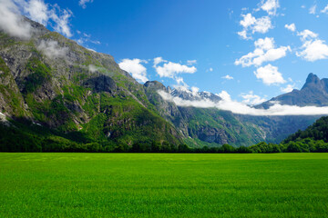 Mountains and nature of Norway. Summer and sunny day. Green valley and white clouds. Blue sky. Snow...