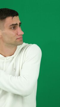 man feels acute pain in elbow joint. Sports and injury concept. Dislocated arm, shoulder pain. emotions of a handsome man guy on a green background chromakey close-up dark hair young man