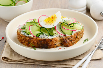 Sandwich with egg, cucumber, radish and cream cheese on whole grain bread. Healthy breakfast. Selective focus