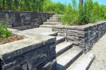 Luxury landscaping with natural stone retaining wall and coping, wide steps and landing.