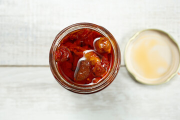 A top down view of an open jar full of sun-dried tomatoes.