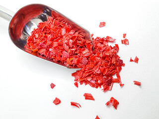 shredded red plastic waste ready for recycling, isolated on white background