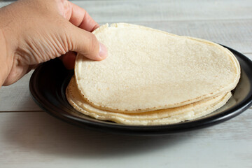 A view of a hand lifting a corn tortilla.