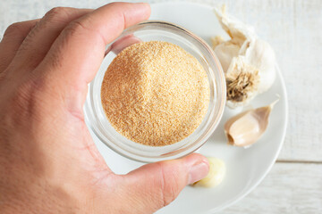 A top down view of a hand holding a small bowl of garlic powder.