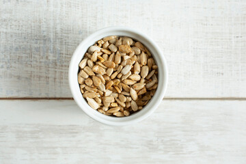 A top down view of a small bowl filled with roasted sunflower seeds.