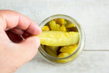 A top down view of a hand pulling out a pickle from a jar.