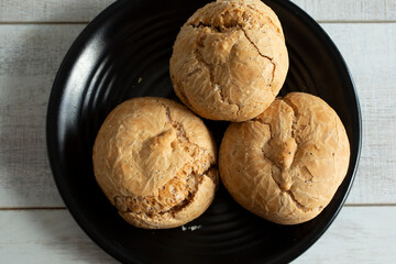 A top down view of gluten-free rolls on a black plate.