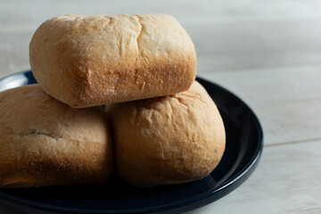 A closeup view of a stack of gluten-free rolls on a black plate.