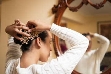 Woman putting hairpin in her hair in front of mirror