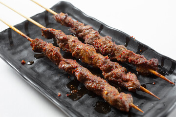 A view of a plate of spicy pork skewers.