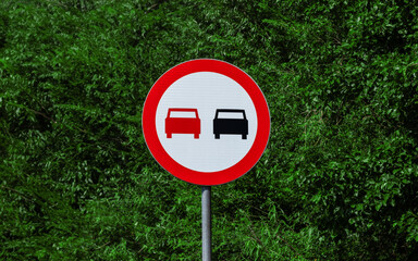 Road sign prohibiting overtaking against a background of trees 