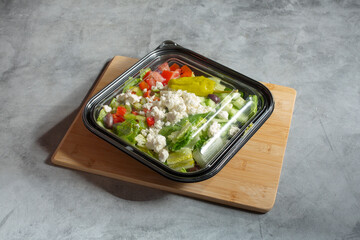 A view of a Greek salad in a plastic to go container.