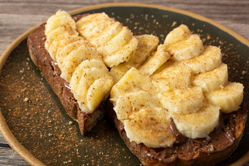 A view of a plate of sliced bananas on pumpernickel toast.