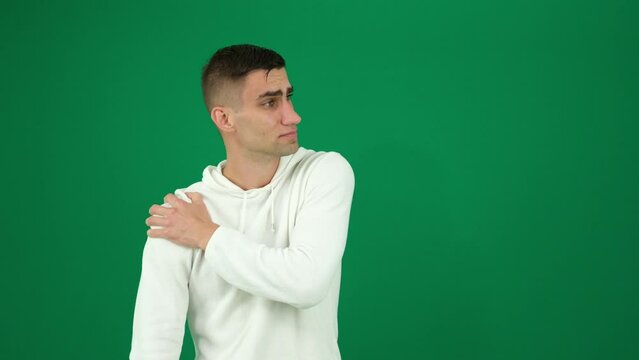 man feels acute pain in elbow joint. Sports and injury concept. Dislocated arm, shoulder pain. emotions of a handsome man guy on a green background chromakey close-up dark hair young man