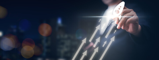 Businessman drawing rocket with white arrow pointing upwards with city background. Concept of progress and growth, as the rocket is being launched into the sky.