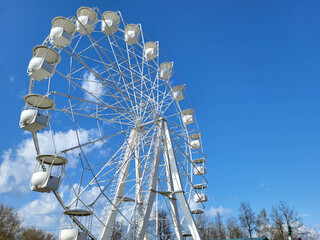 A white Ferris wheel against a blue sky background.